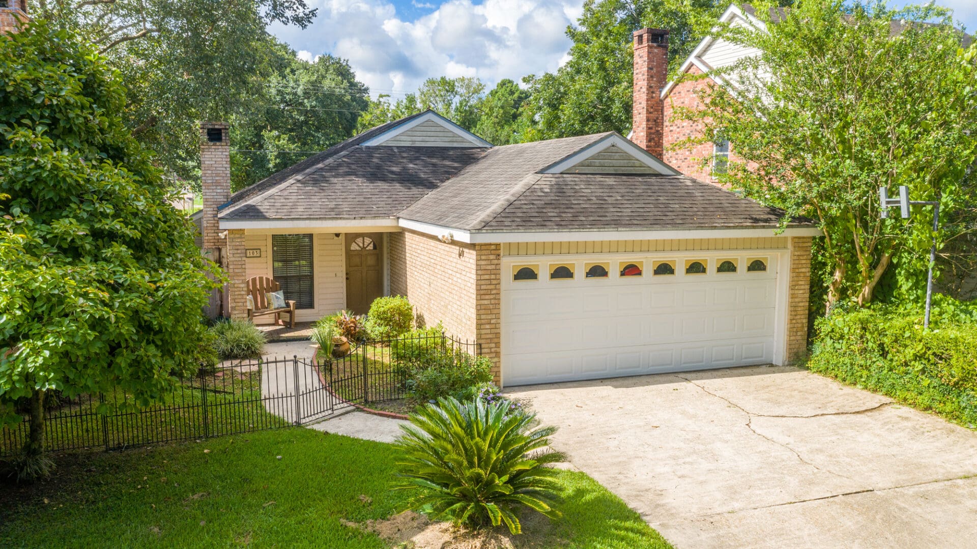 A house with a driveway and trees in the background